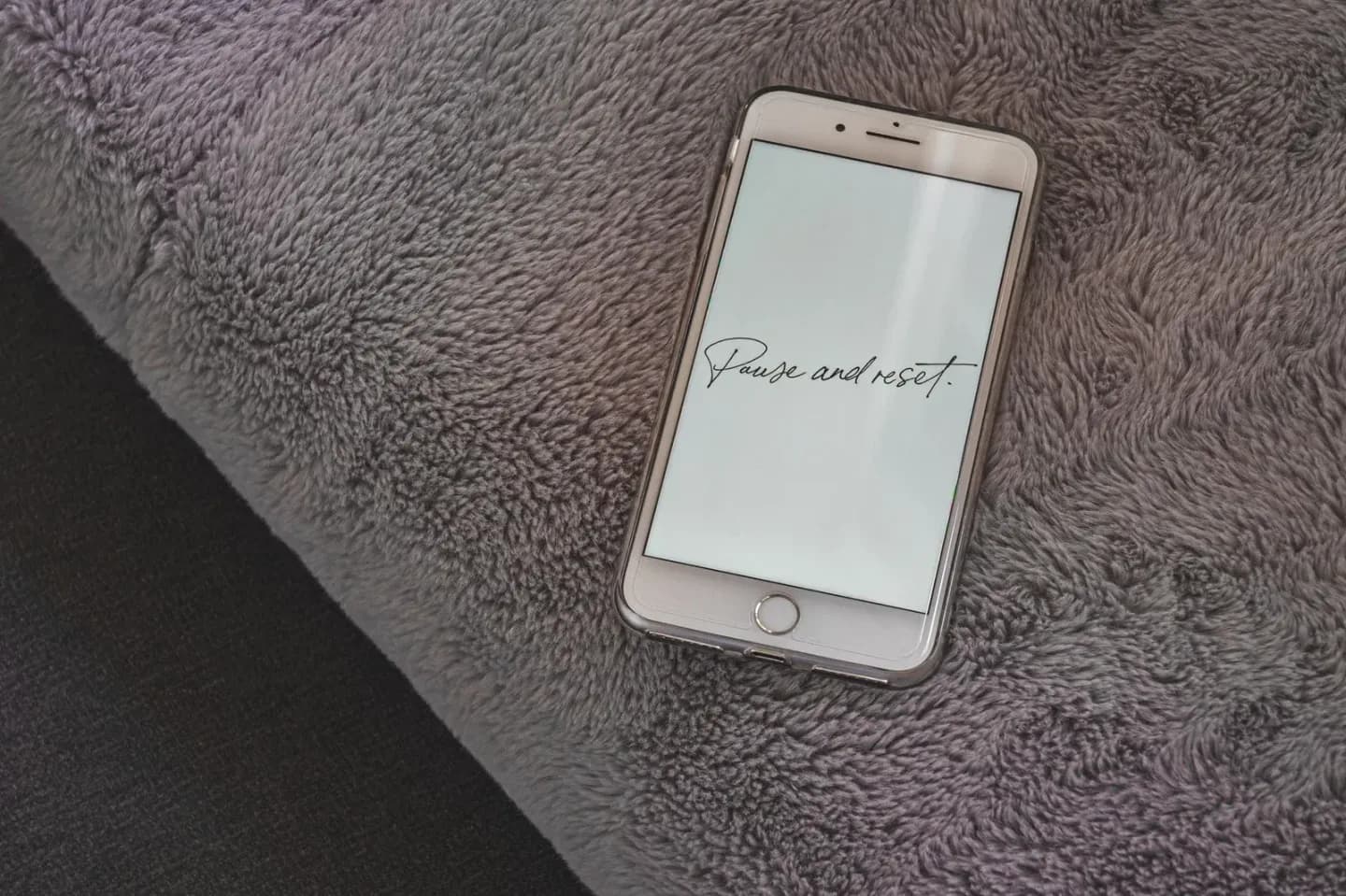 Smartphone on a gray blanket with "Pause and reset." written on the screen